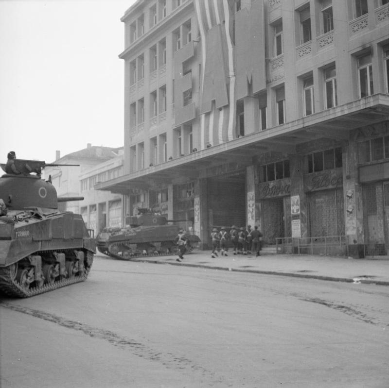 Британские танки и пехота врываются в здание афинского правления ЭАМ, по улице Кораи, в центре города. Фотография NA 20518 из коллекции ImperialWarMuseums.