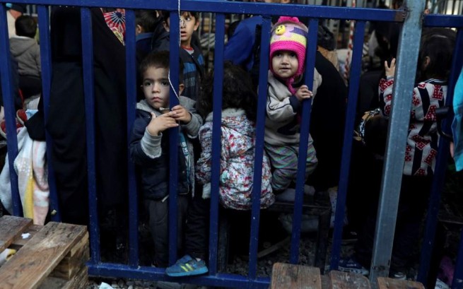Дети стоят рядом с металлическим барьером, поскольку вновь прибывшие беженцы и мигранты ожидают регистрации в лагере Мория на острове Лесбос, Греция, 27 ноября 2019 года [Elias Marcou / Reuters]