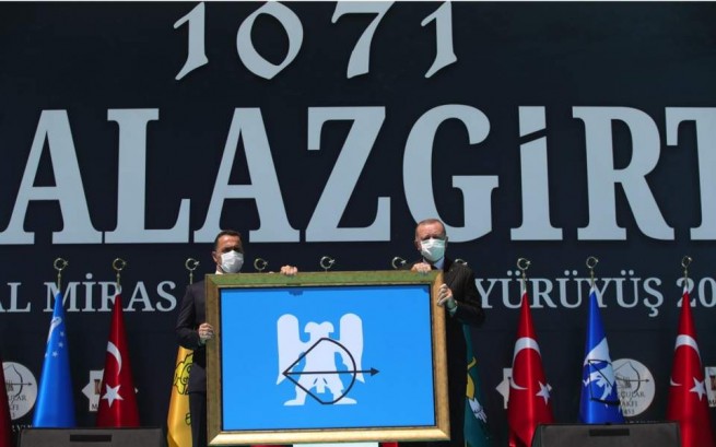 Президент Турции Реджеп Тайип Эрдоган (справа) получает сельджукский флаг на торжествах по случаю годовщины битвы при Манцикерте 1071 года, во время которой турецкие сельджуки разбили византийские силы и вошли в Анатолию в Малазгирте на востоке Турции в среду.
