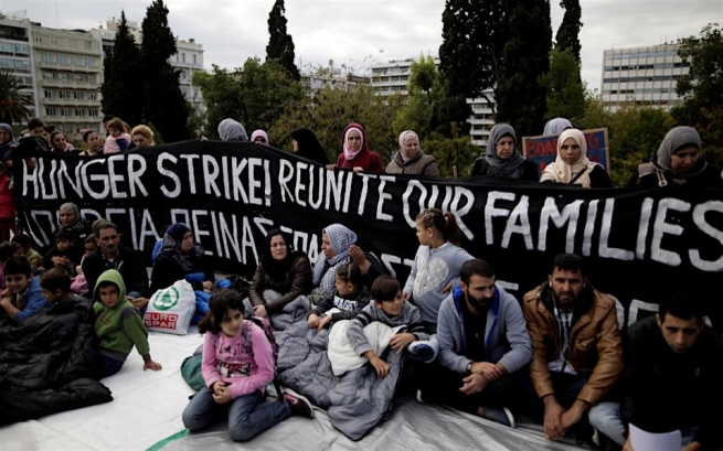 Мигранты-беженцы, желающие воссоединения с членами семьи в Германии, сидят перед баннером, объявляя голодовку во время протеста возле здания парламента в Афинах в среду