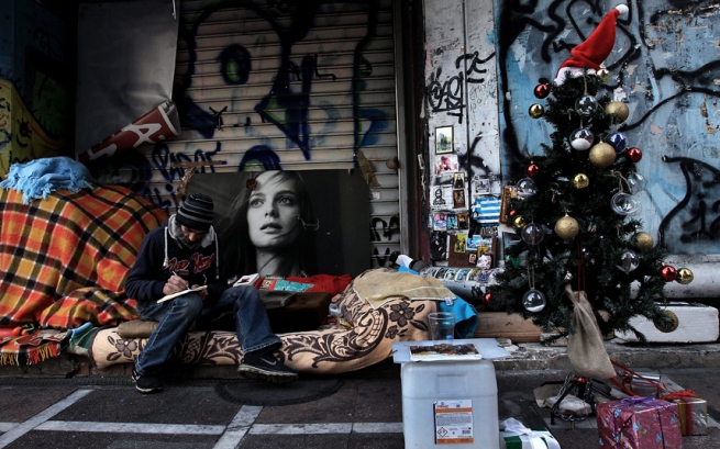 Афины: Бездомный человек несет свое Рождественское приветствие на улицу Стадиу